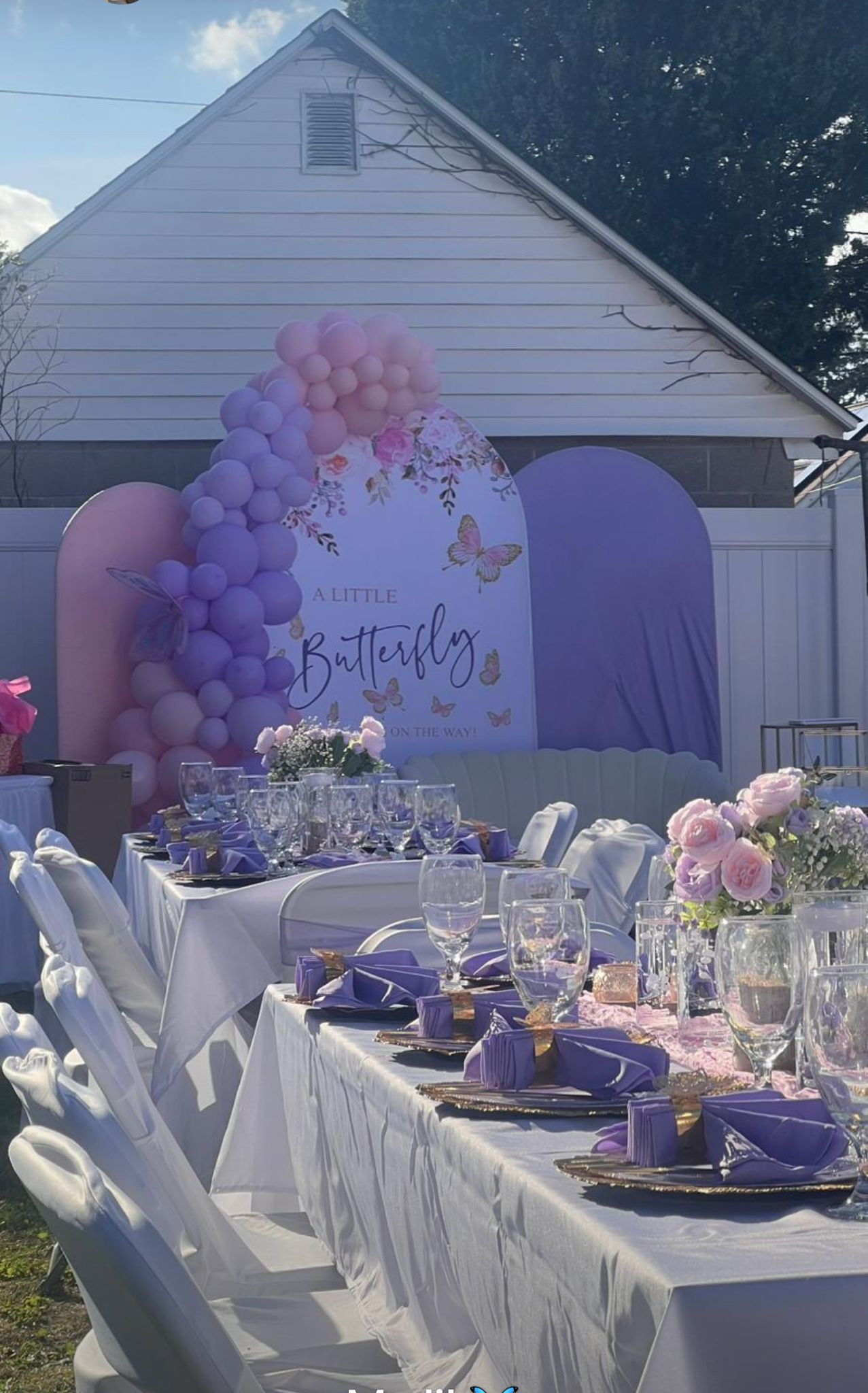 Outdoor lavender tables with balloon arch and 'A Little Butterfly' backdrop